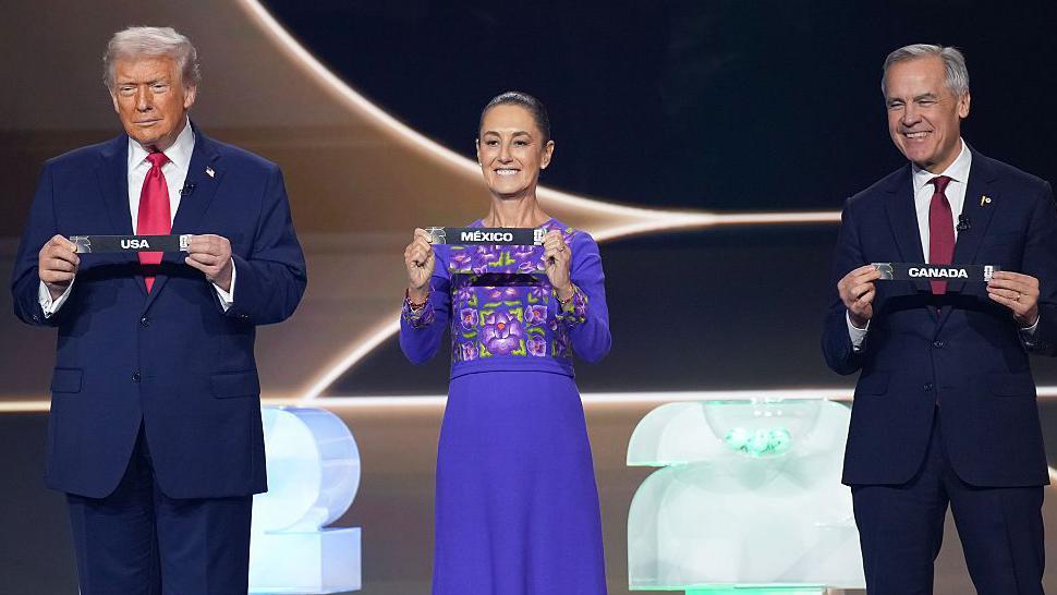 Donald Trump, Claudia Sheinbaum y Mark Carney, cada uno sosteniendo el nombre de su pa&iacute;s en un evento por el Mundial 2026