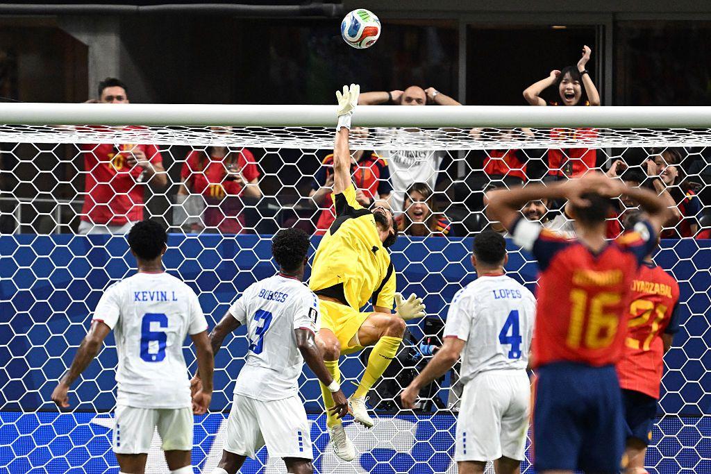Vozinha alza la mano para detener un bal&oacute;n enviado por jugador vestido con la camiseta de Espa&ntilde;a. 