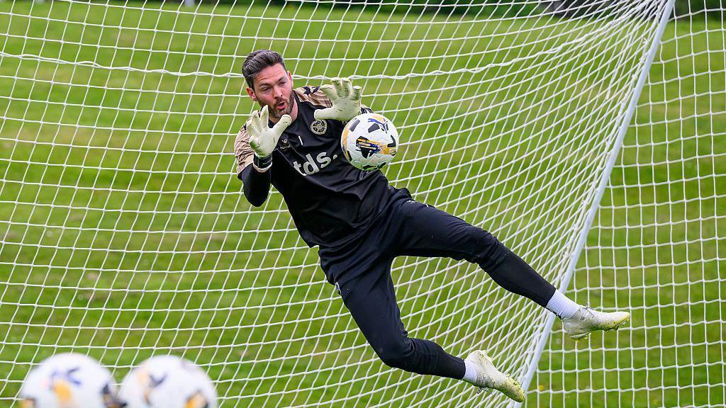 Craig Gordon realiza una parada mientras entrena con su club, el Heart of Midlothian escoc&eacute;s, en Edimburgo el 7 de mayo. Viste de negro y salta con los brazos extendidos para detener el disparo.