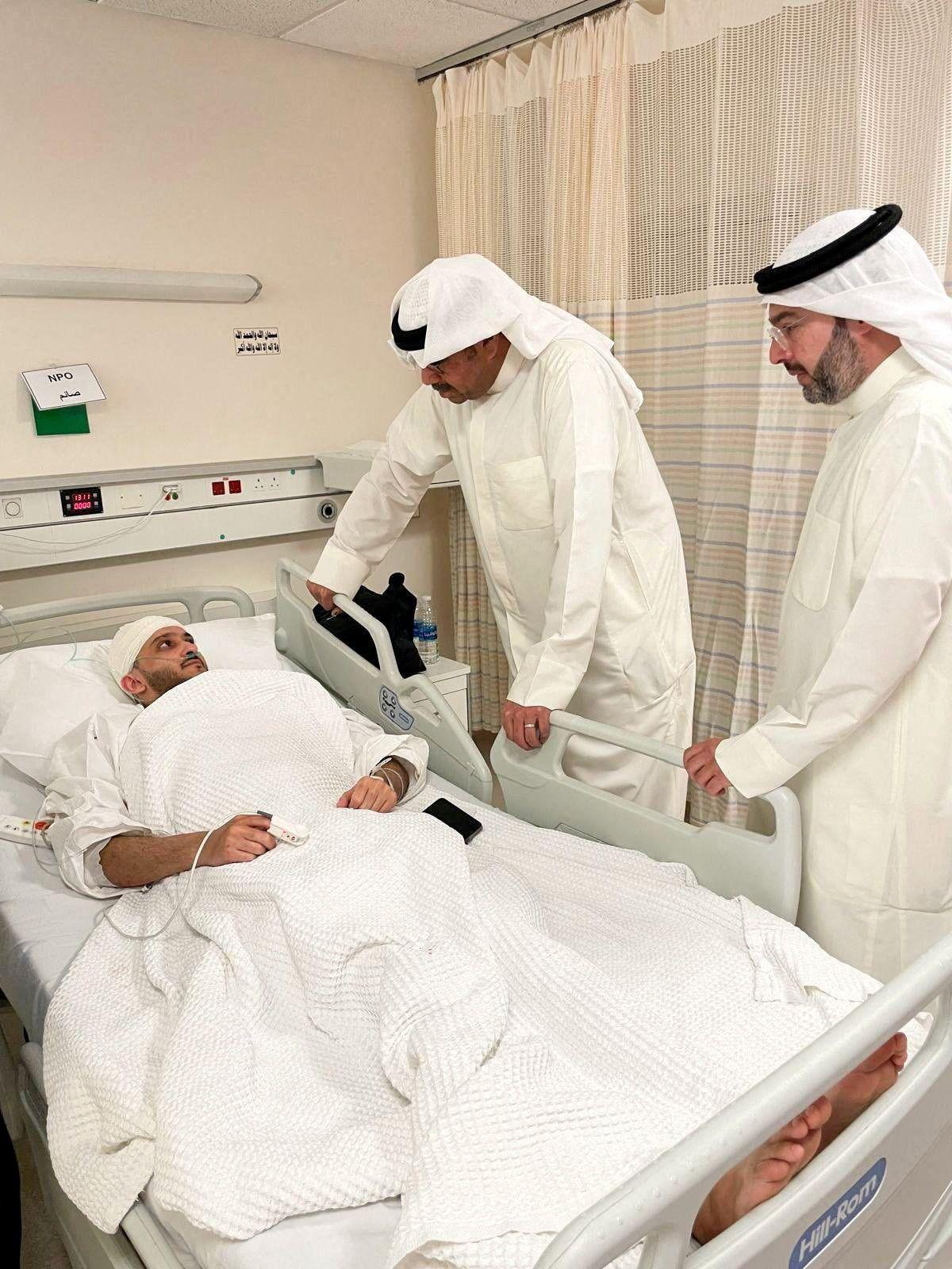 El ministro de Defensa kuwait&iacute;, el jeque Abdullah Ali Abdullah al Salem al Sabah, un hombre con t&uacute;nica blanca mira a una persona en una cama, con la cabeza con vendas.