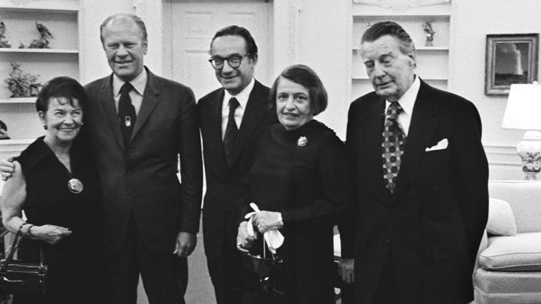 De izquierda a derecha aparecen Rose Goldsmith (madre de Alan Greenspan), el presidente Gerald R. Ford, Alan Greenspan, la escritora Ayn Rand y su esposo Charles Francis &laquo;Frank&raquo; O'Connor, tras la toma de posesi&oacute;n de Greenspan como presidente del Consejo de Asesores Econ&oacute;micos en el Despacho Oval.