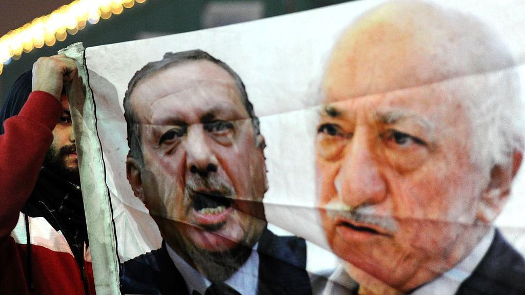 Un manifestante turco (izquierda) sostiene una pancarta con fotos de Recep Tayyip Erdogan (centro) y Fethullah Gulen (derecha) durante una manifestaci&oacute;n contra el gobierno el 30 de diciembre de 2013 en Estambul.