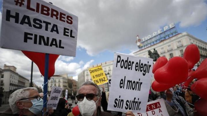 Personas se manifiestan en Espa&ntilde;a a favor de la eutanasia. Llevan carteles donde se lee "Libres hasta el final" y "Poder elegir el morir sin sufrir". 