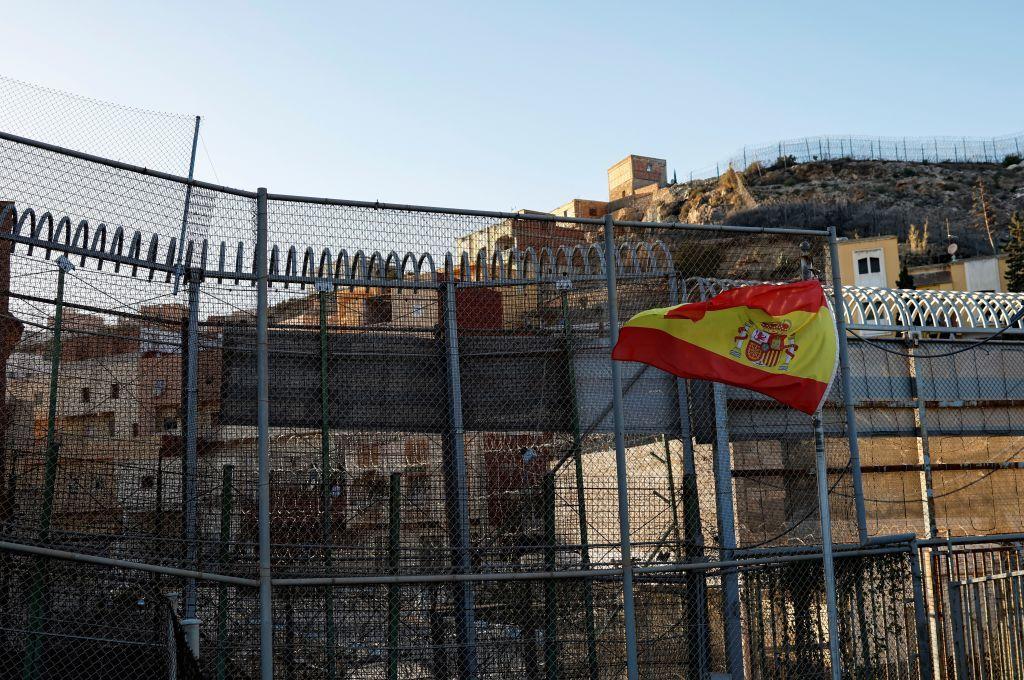 Esta fotografía, tomada el 24 de febrero de 2024 en Melilla, muestra una bandera de España en una valla cerca de un paso fronterizo cerrado entre Marruecos (arriba) y el enclave español de Melilla, en el norte de África.