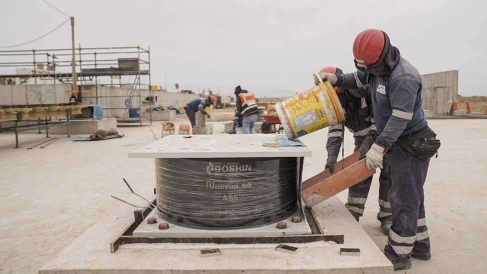 Trabajadores colocando aisladores s&iacute;smicos durante la construcci&oacute;n del nuevo terminal del aeropuerto internacional en Lima.