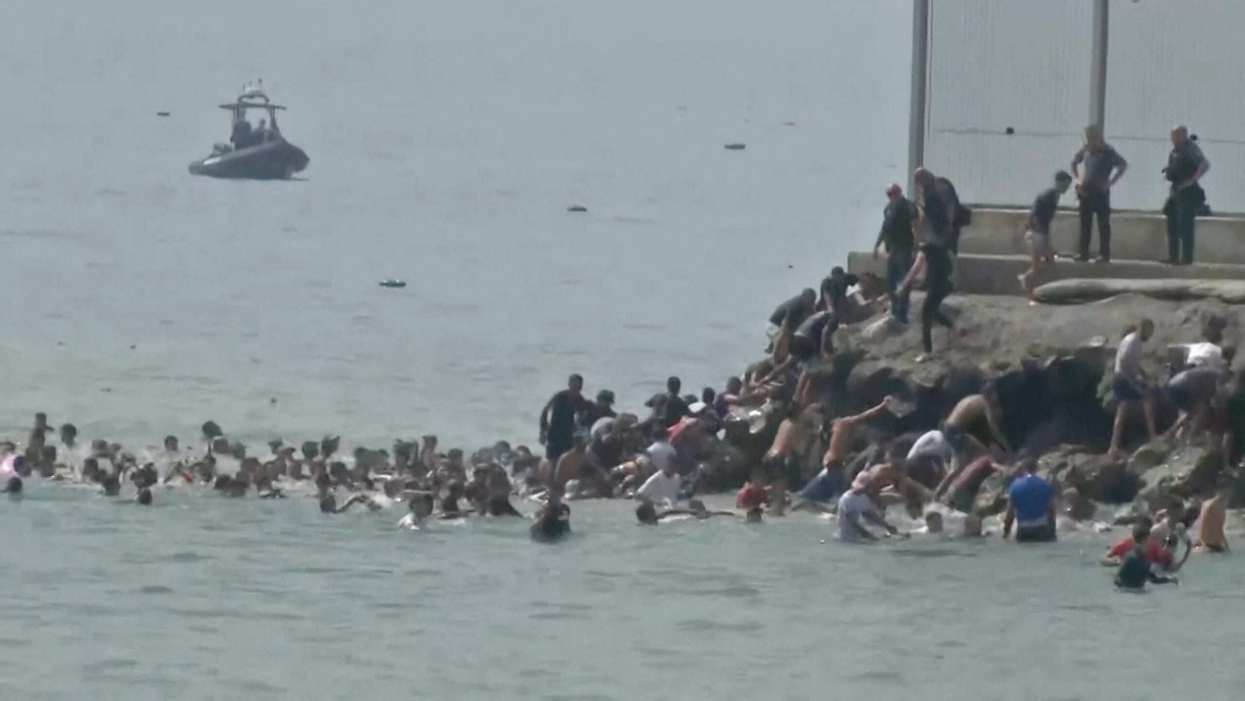 Migrantes cruzan a nado la frontera española de Ceuta desde el lado marroquí y trepan por las rocas para llegar a la valla fronteriza, en Ceuta, España, 30 de julio de 2026, 