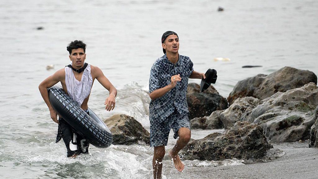 Dos migrasntes saliendo de la playa. 