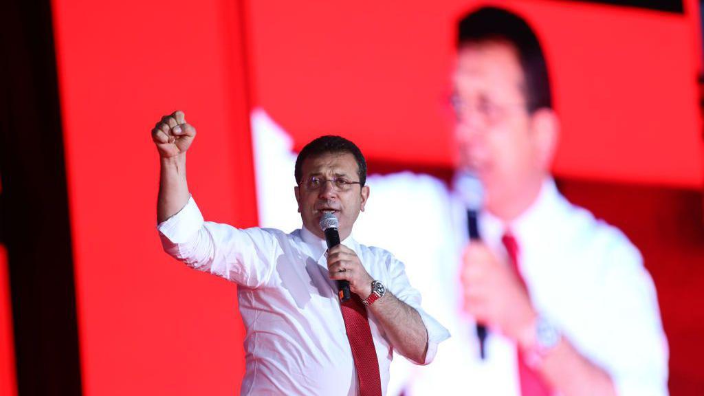 El alcalde de Estambul, Ekrem İmamoğlu, interviene en un acto p&uacute;blico en mayo de 2023, gesticulando con el pu&ntilde;o en alto mientras se dirige a la multitud.