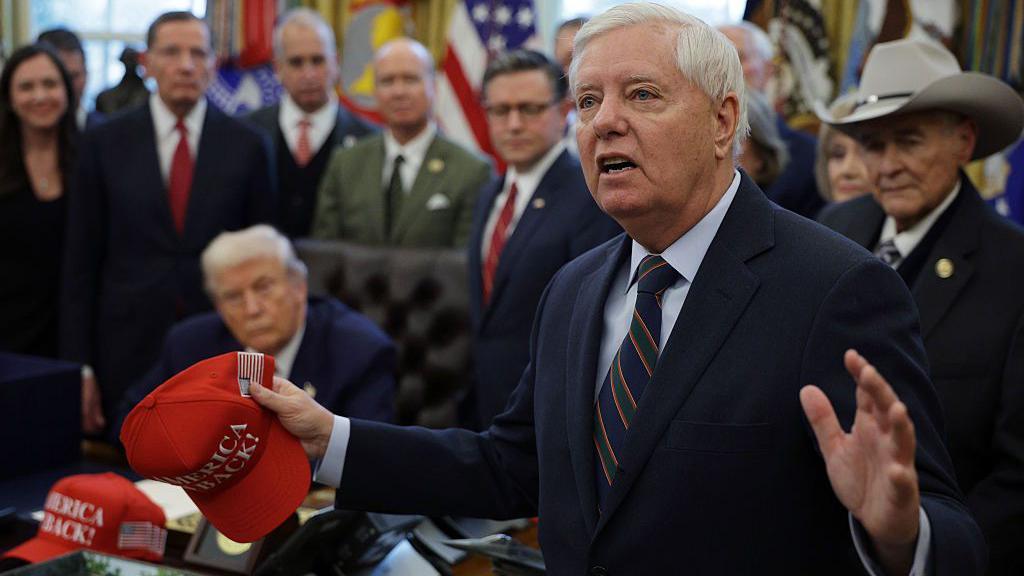 Lindsey Graham pronuncia un discurso durante la firma de un proyecto de ley en el Despacho Oval. El presidente Donald Trump se puede ver al fondo.