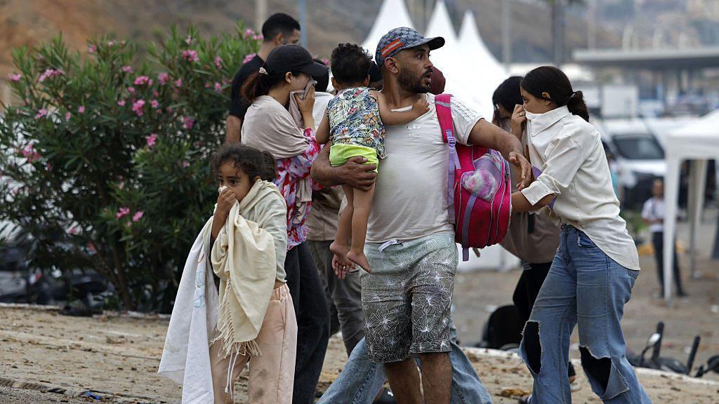 Un grupo de personas, entre ellas dos menores de edad, reaccionan cubriéndose la boca en el lugar de los enfrentamientos cerca de Fnideq, en la frontera entre Marruecos y España, el 31 de julio de 2026. 