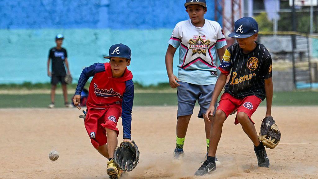 Ni&ntilde;os jugando b&eacute;isbol en un campo de la urbanizaci&oacute;n 23 de enero de Caracas.