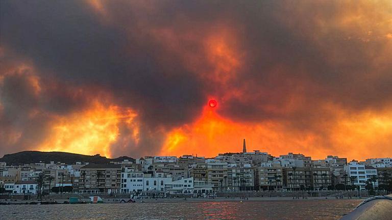 El fuego resplandece detr&aacute;s de una ciudad costera en Andaluc&iacute;a.