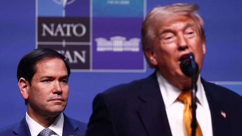 Donald Trump habla ante un micr&oacute;fono mientras detr&aacute;s de &eacute;l, a su lado izquierdo, est&aacute; el secretario de Estado, Marco Rubio.
