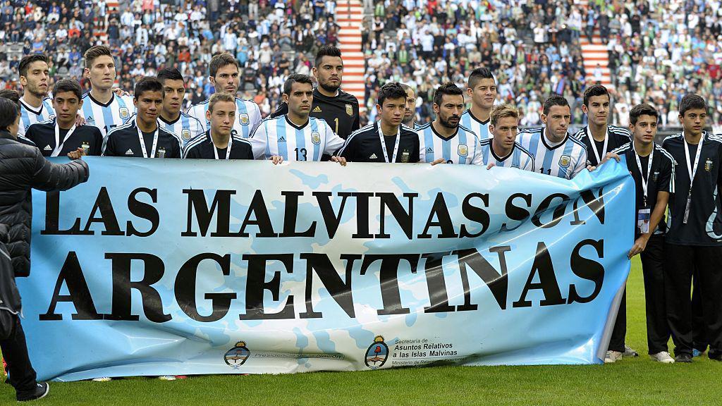 La selecci&oacute;n argentina tras una pancarta que dice "Las Malvinas son argentinas".