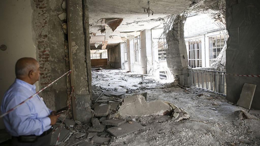 Un hombre observa los da&ntilde;os en el interior del Parlamento turco tras el ataque con helic&oacute;pteros ocurrido el 15 de julio de 2016. Se aprecia un gran agujero en una pared, con ventanas destrozadas, cristales rotos y escombros esparcidos por todo el edificio.