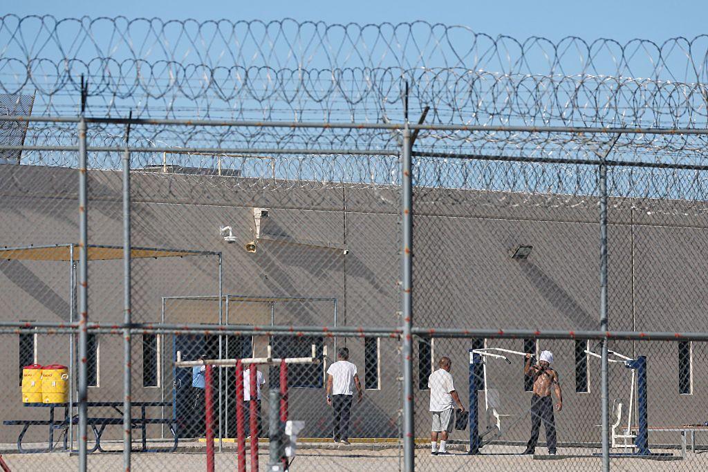 A trav&eacute;s de las verjas y el alambre de concertina se ve a varios detenidos en el patio del centro de procesamiento del ICE en Adelanto, California, Estados Unidos, el 11 de julio de 2025. (Foto: PATRICK T. FALLON/AFP v&iacute;a Getty Images)