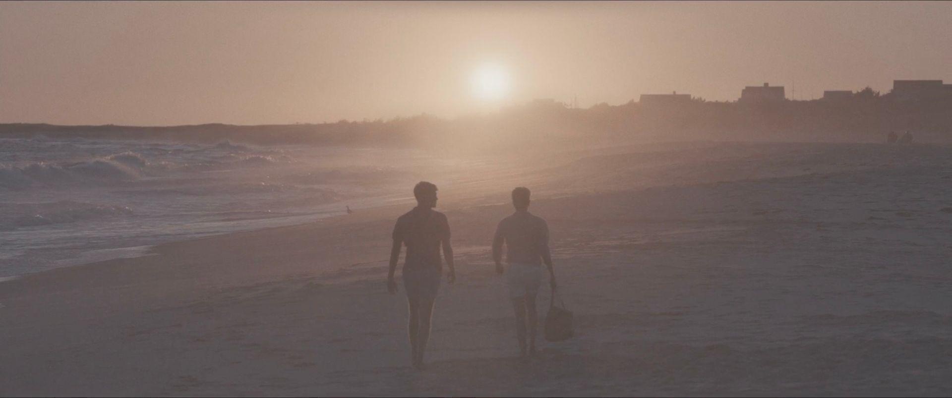 Fotograma del documental Bring Me The Beauties en el que se ve a dos personas caminando en una playa. Hay una suerte de neblina.