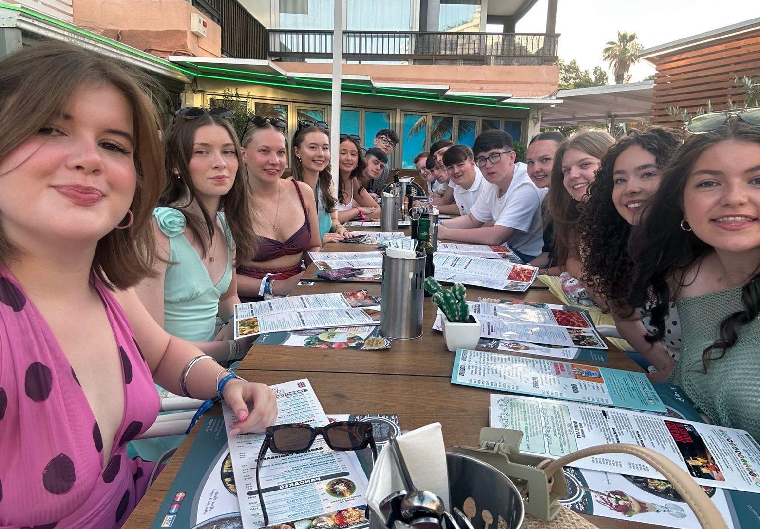 Un grupo de j&oacute;venes sentados en una mesa en un restaurante en un pa&iacute;s extranjero.