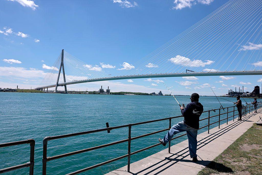 Personas pescando en un día despejado, bajo el puente Gordie Howe