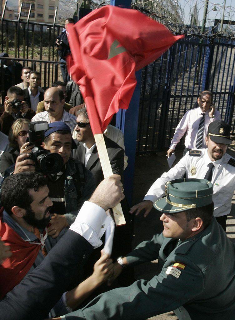 Marroquíes que se manifiestan (izquierda) se enfrentan a agentes de la Guardia Civil española mientras intentan entrar a la fuerza en territorio español —el 6 de noviembre de 2007— desde la localidad de Beni Nssar, en la frontera con el enclave español norteafricano de Melilla (derecha), en protesta por la visita de dos días de los reyes de España, Juan Carlos y Sofía, a los enclaves españoles de Melilla y Ceuta.