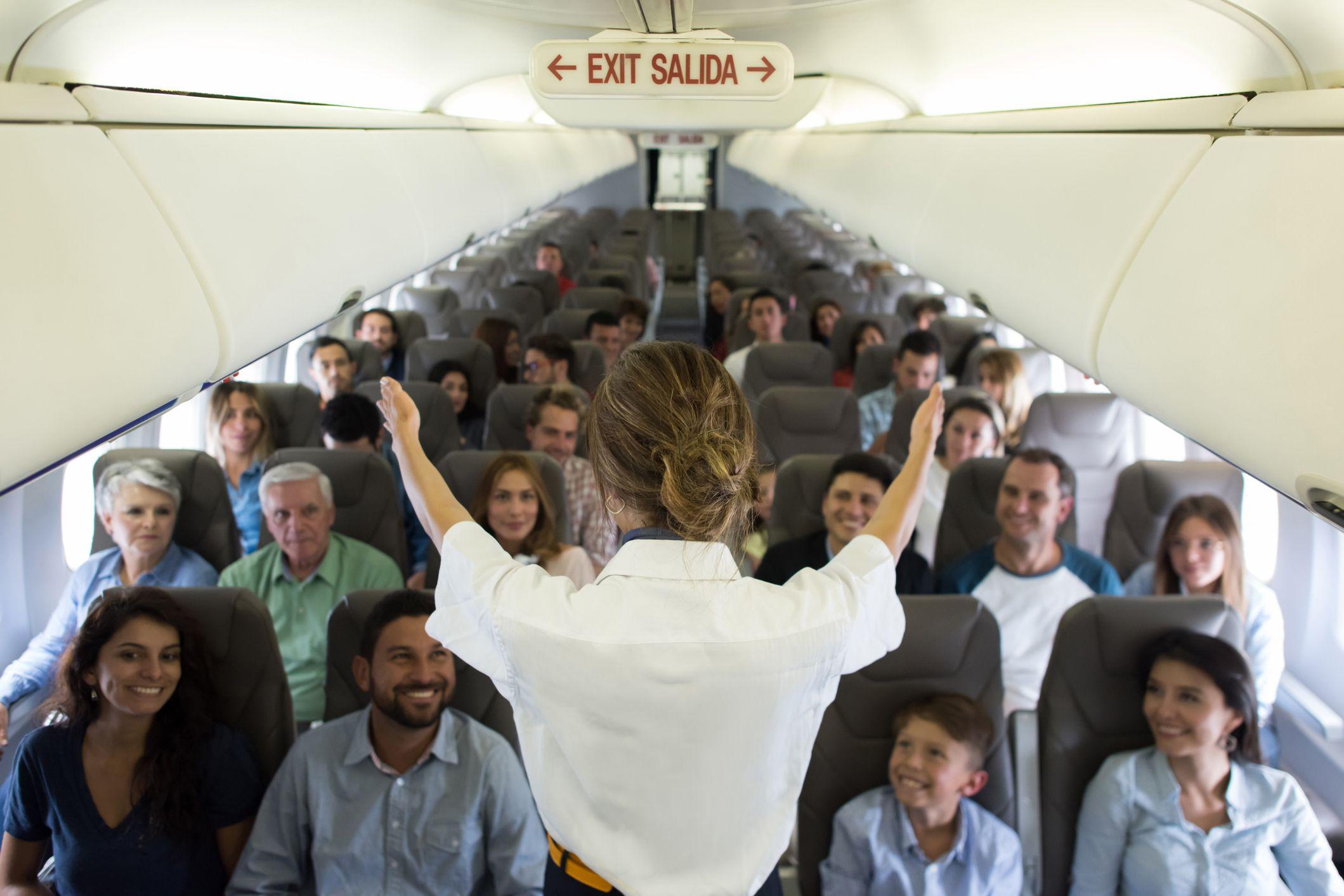 Una azafata muestra dónde están las salidas de emergencia en un avión.