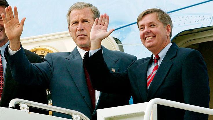 Graham sonr&iacute;e y saluda mientras sube a un avi&oacute;n con Bush.