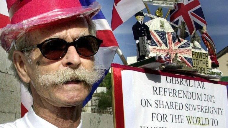 Un gibraltare&ntilde;o brit&aacute;nico sostiene un cartel exhortando a votar "No" en el referendo sobre la soberan&iacute;a compartida entre Espa&ntilde;a y Reino Unido