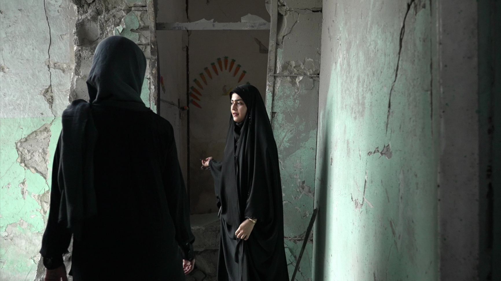Amaineh Nademi camina por uno de los pasillos que aún se conservan de la escuela primaria Shajareh Tayyebeh en Minab. Viste un chador negro y le muestra a Nawal al Maghafi, reportera de la BBC, los daños en la escuela. Las paredes de hormigón están agrietadas y anteriormente habían sido pintadas de verde pastel.