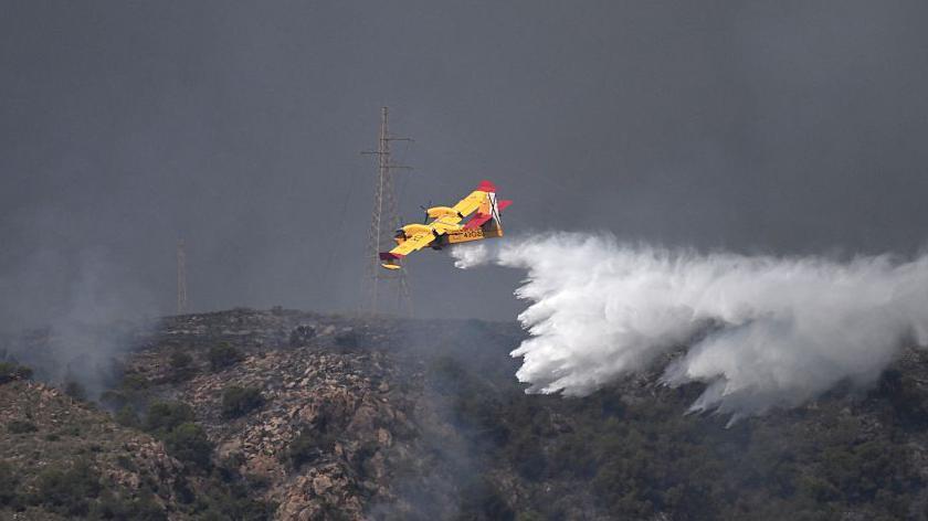 Un hidroavi&oacute;n de color amarillo ayuda en las tareas de extinci&oacute;n del fuego arrojando agua desde el aire. 