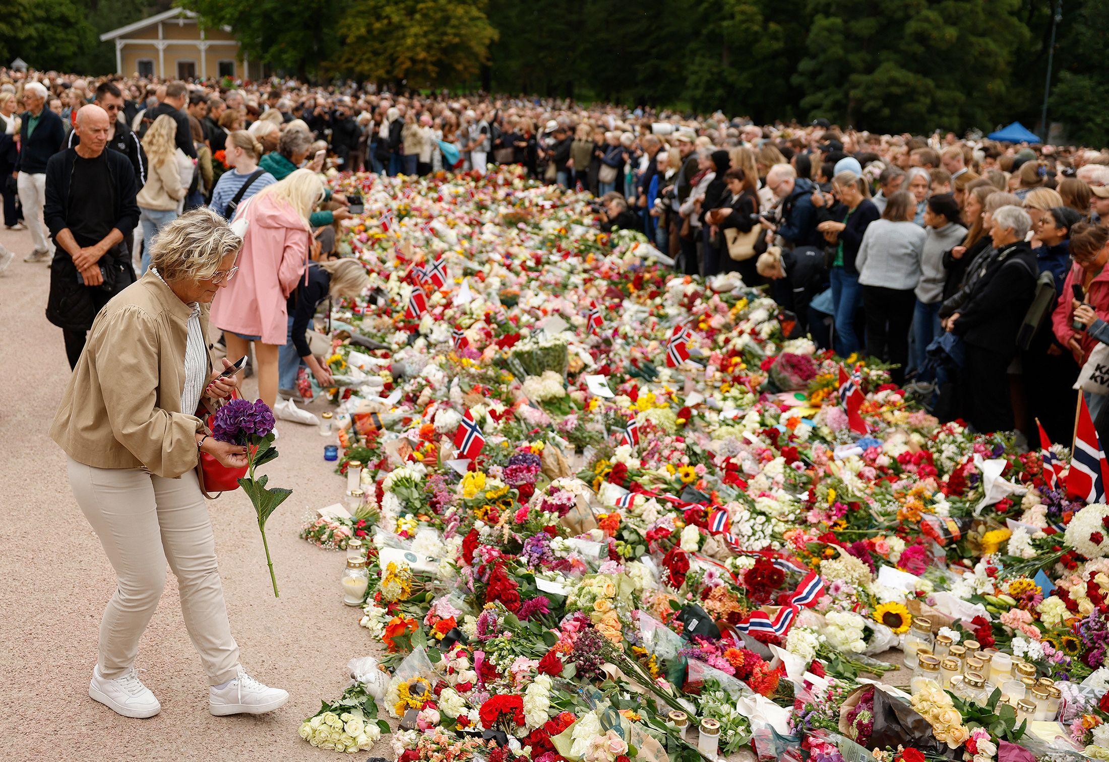 Una persona deposita una flor en un memorial improvisado en la plaza del Palacio Real de Oslo para rendir homenaje al rey Harald V de Noruega, fallecido recientemente.