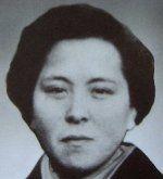 Retrato en blanco y negro de Miyoshi. Mira fijamente a la cámara. Tiene el pelo corto y oscuro y una expresión seria.