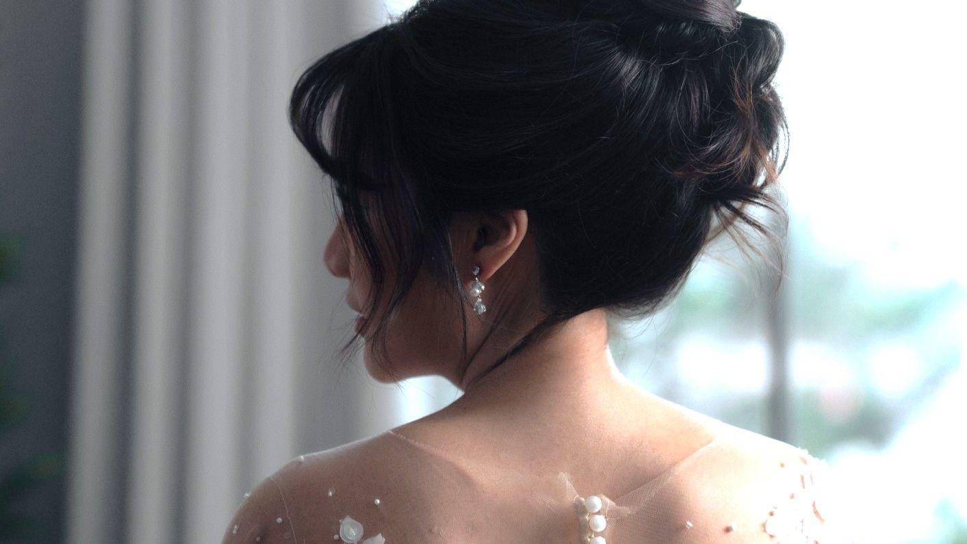 Una novia con el cabello recogido mira por encima del hombro.