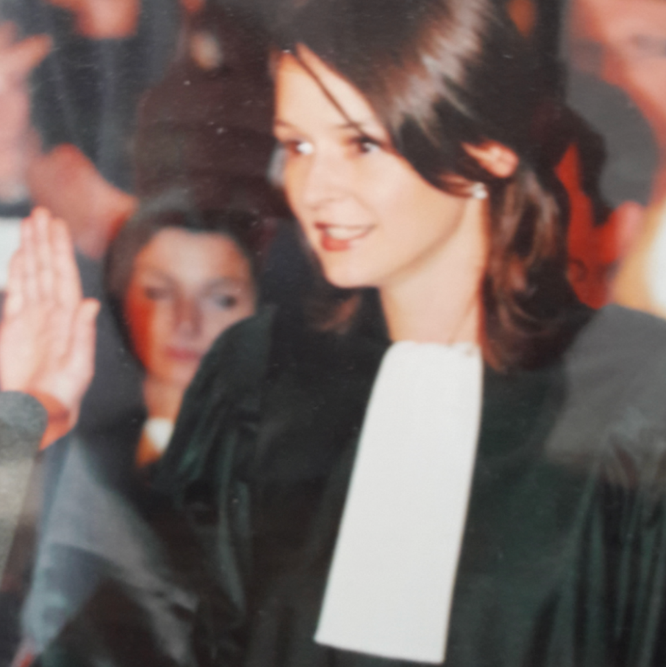 Una fotografía en primer plano muestra a una joven Audrey en lo que parece ser un evento concurrido en un espacio cerrado. Sonríe amablemente y mira hacia un lado. Al fondo, detrás de ella, se ven varias personas desenfocadas.