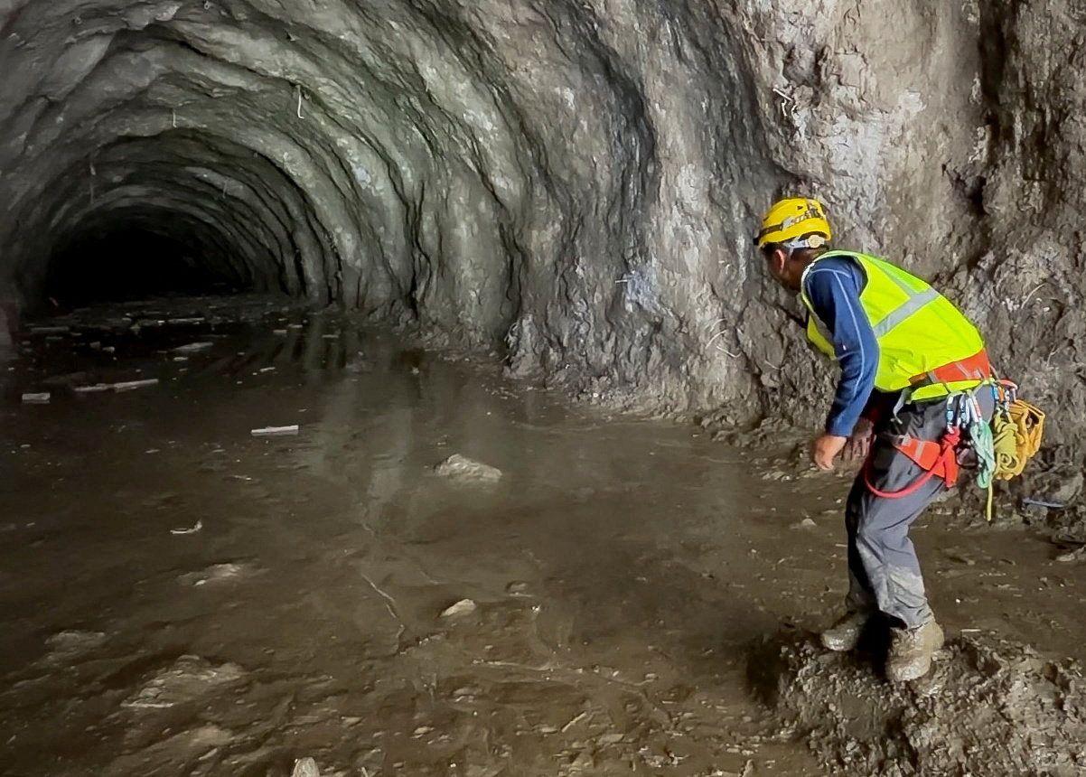 Un rescatista en un túnel de una central hidroeléctrica inundado por agua y barro.