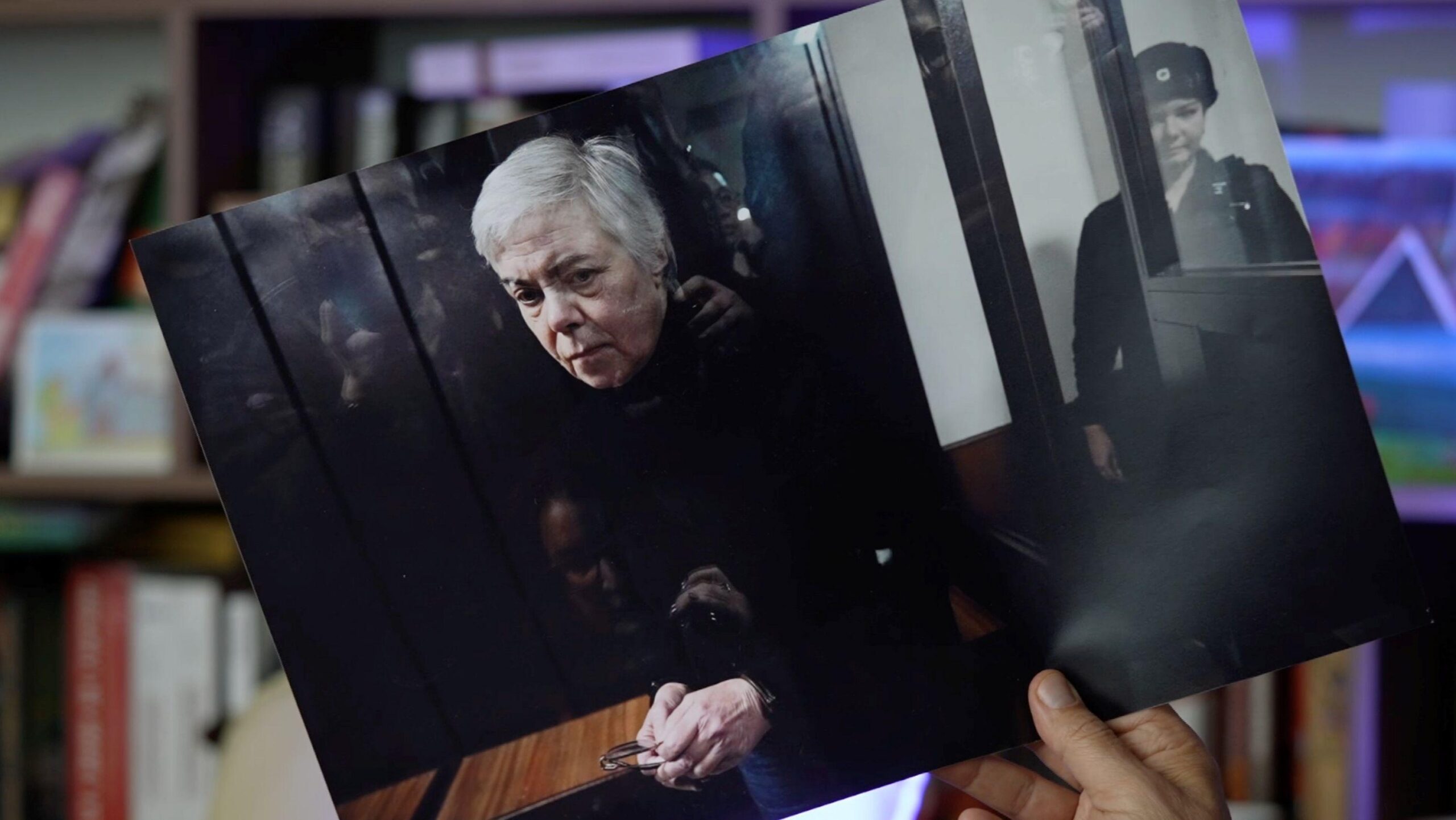 Una mano sostiene una fotografía impresa de Nadezhda Buyanova, una pediatra ucraniana de 68 años, sentada en el banquillo de los acusados en el tribunal, bajo custodia. Foto de archivo.