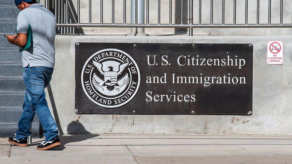 Un peatón pasa frente a un letrero exterior y un sello oficial que identifican el edificio de la oficina de campo de los Servicios de Ciudadanía e Inmigración de EE. UU. (USCIS) en Salt Lake City, Utah, Estados Unidos, el 21 de agosto de 2026. (Foto de Charles-McClintock Wilson/NurPhoto vía Getty Images)