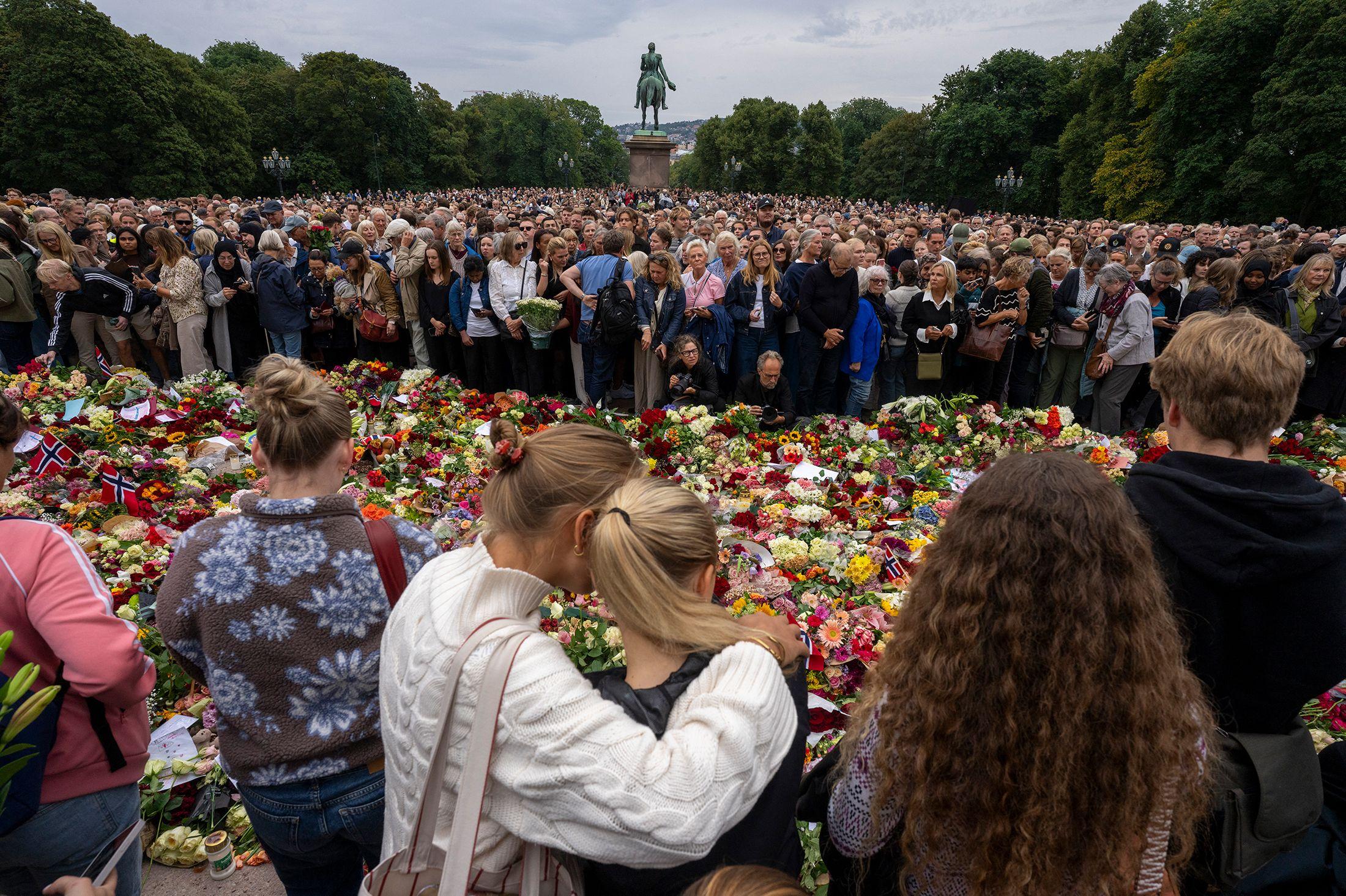 Personas reunidas ante un memorial improvisado de flores para rendir homenaje al rey Harald V de Noruega, fallecido, en la plaza del Palacio Real de Oslo el 28 de agosto de 2026.