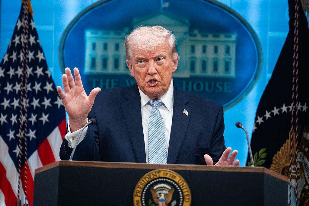 Donald Trump pronuncia un discurso desde un podio. Viste traje azul con camisa clara y corbata celeste.