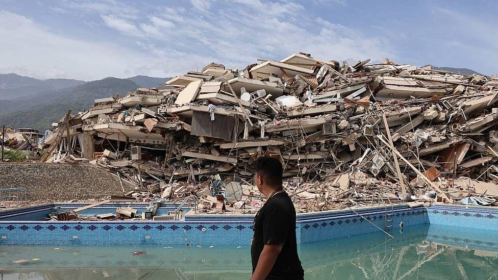 Una mujer pasa frente a una montaña de escombros tras el colapso de un edificio en el estado de La Guaira, uno de los más afectados por los terremotos en Venezuela.