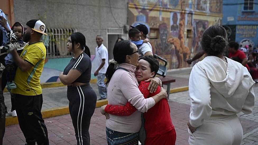 Una mujer consuela a un niño en la calle en Caracas. Tambén se ve a otras personas que permanecen en la calle por temor a réplicas