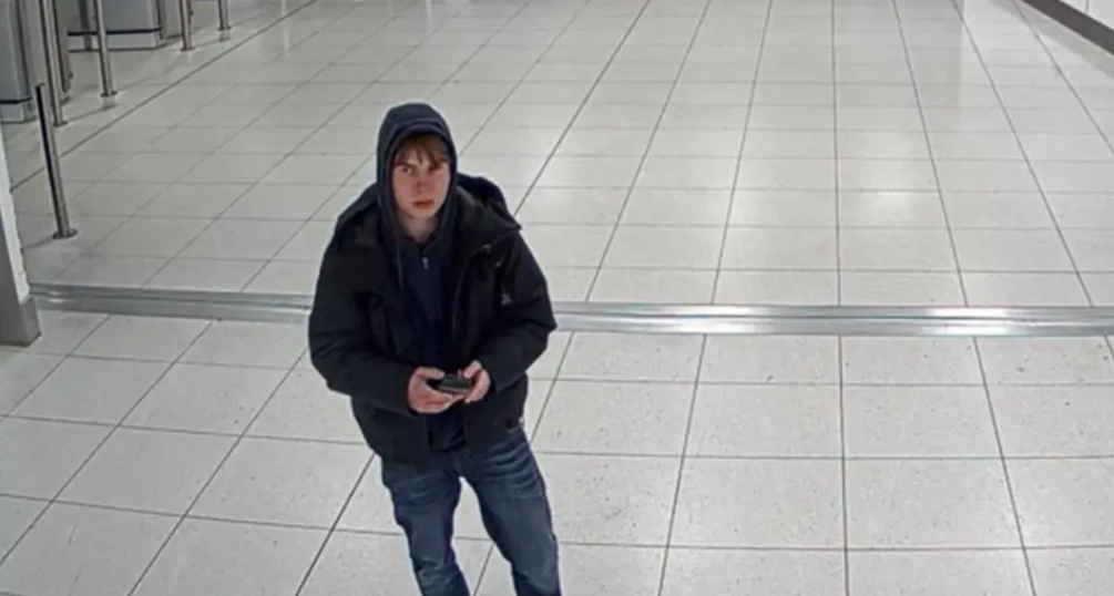 Johannes Natland lleva una sudadera con capucha, una chaqueta oscura y vaqueros. Está en un aeropuerto y tiene un teléfono en la mano.