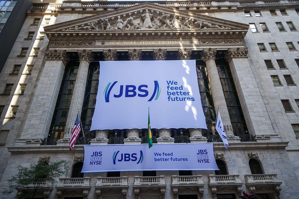 Dos grandes letreros blancos con el logo de JBS y el lema 