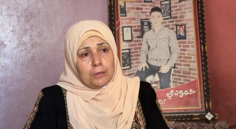 Aida al Drimli en su casa con un cuadro de su hijo atrás de ella mientras habla. 