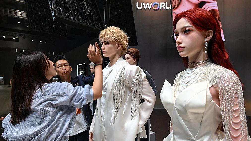 Una mujer inspecciona una vitrina que muestra los robots humanoides realistas de UBTech.