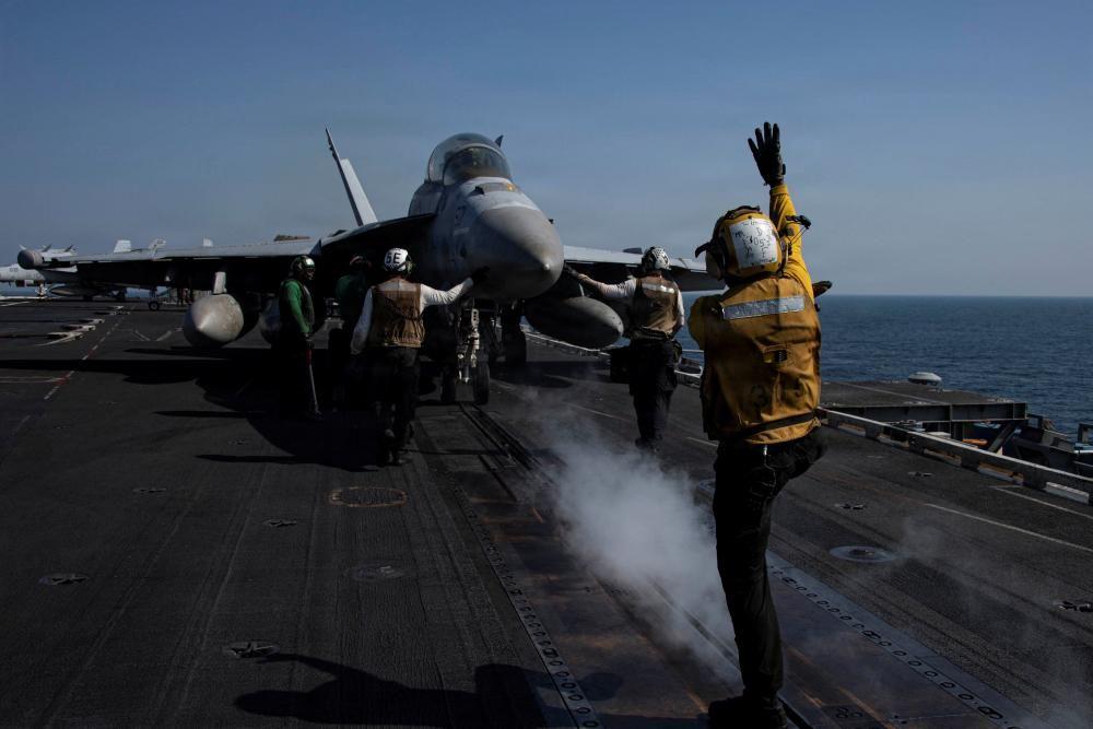 Personal del USS Abraham Lincoln frente a un jet militar