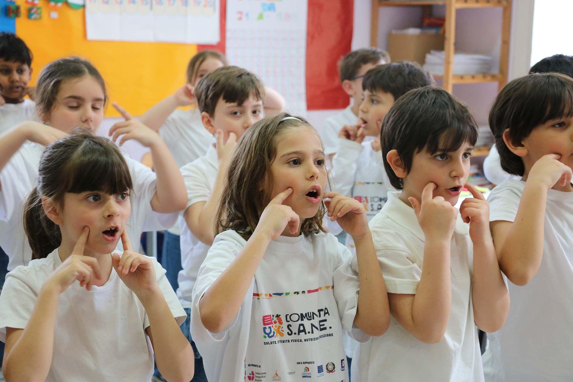 Niños de primaria hacen el gesto italiano que indica que la comida está rica.