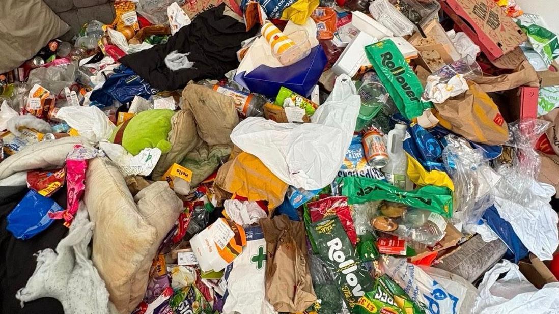Una enorme pila de basura compuesta por cajas, bolsas de basura y envases de comida.