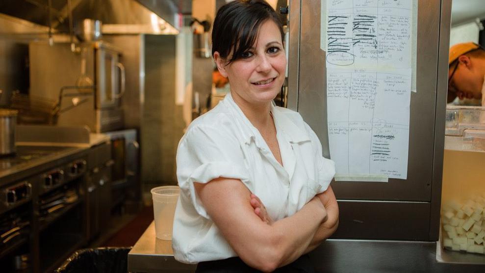 Amanda Cohen está de pie en la cocina de su restaurante con los brazos cruzados.