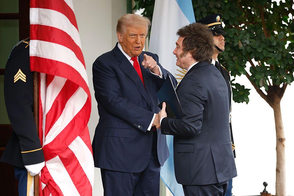 Donald Trump y Javier Milei se dan la mano. 