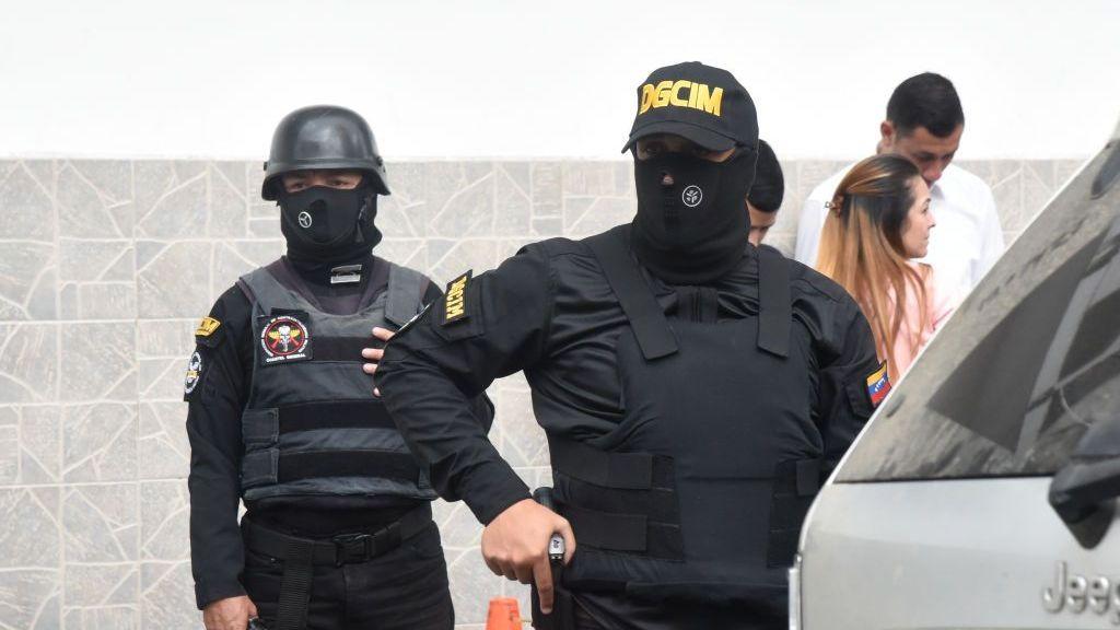 Dos agentes vestidos de negro y enmascarados de la DGCIM.